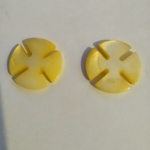 May include: Two yellow and white shell buttons with a four-pointed star design.