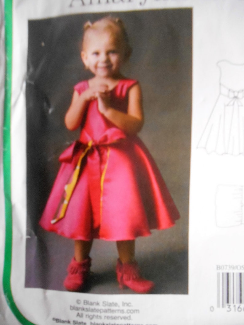 Puede incluir: Una ni&ntilde;a peque&ntilde;a con un vestido rosa brillante con una cinta amarilla y blanca atada alrededor de la cintura. Lleva mocasines rojos con flecos. El vestido es sin mangas y tiene una falda completa.