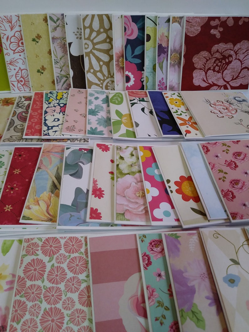May include: A large collection of rectangular greeting cards featuring a diverse array of printed patterns, including floral motifs, geometric shapes, and botanical designs in various colors such as red, pink, blue, yellow, green, and white.