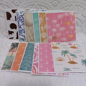 May include: A collection of square greeting cards featuring various coastal and tropical patterns, including palm trees, seashells, coral, anchors, and beach scenes in shades of pink, orange, blue, teal, yellow, and brown with white borders.