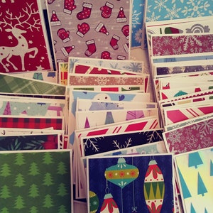 May include: A collection of Christmas cards with various festive designs. The cards feature patterns like reindeer, mittens, snowflakes, Christmas trees, and ornaments. Colors include red, green, blue, and white, creating a cheerful holiday theme.