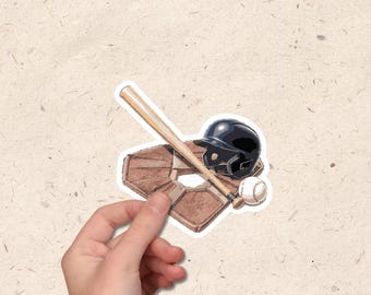 May include: A baseball-themed sticker featuring a brown home plate, a wooden bat, a black helmet, and a white baseball. The sticker is held by a hand against a textured background.