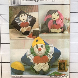 May include: Simplicity Crafts sewing pattern number 8469, one size, for making three different clown pillows. The pattern includes instructions for making a jester clown pillow, a traditional clown pillow, and a clown pillow with a heart. The pattern is from 1987.