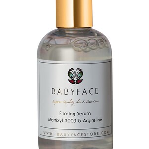 May include: A clear glass bottle with a gold lid and label. The label says "BABYFACE Superior Quality Skin & Hair Care" and "Firming Serum Matrixyl 3000 & Argireline". The bottle is sitting on a white background.