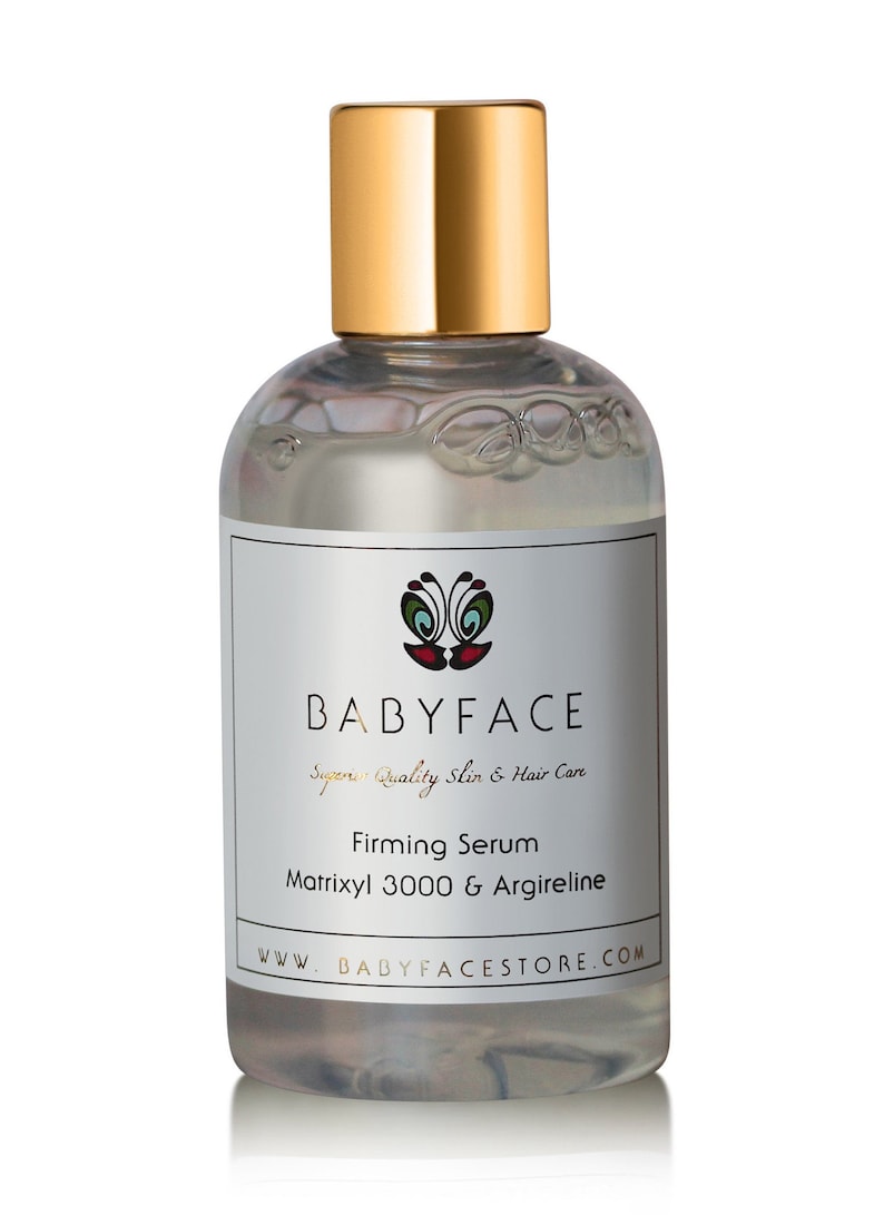 May include: A clear glass bottle with a gold lid and label. The label says "BABYFACE Superior Quality Skin & Hair Care" and "Firming Serum Matrixyl 3000 & Argireline". The bottle is sitting on a white background.