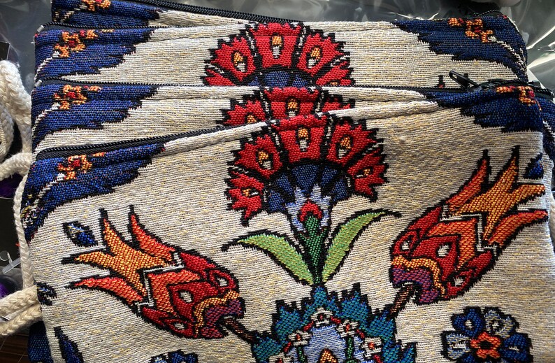 Puede incluir: Una pila de cuatro bolsas de tela coloridas con un dise&ntilde;o floral. Las bolsas tienen cierre de cremallera y est&aacute;n hechas de una tela tejida con fondo blanco y flores rojas, azules, verdes y amarillas.