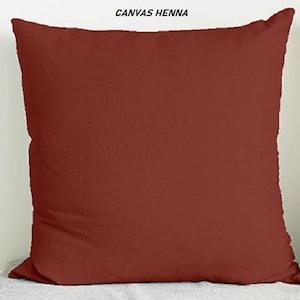 May include: A solid red throw pillow made of canvas fabric. The pillow is a simple, rectangular shape with no embellishments.