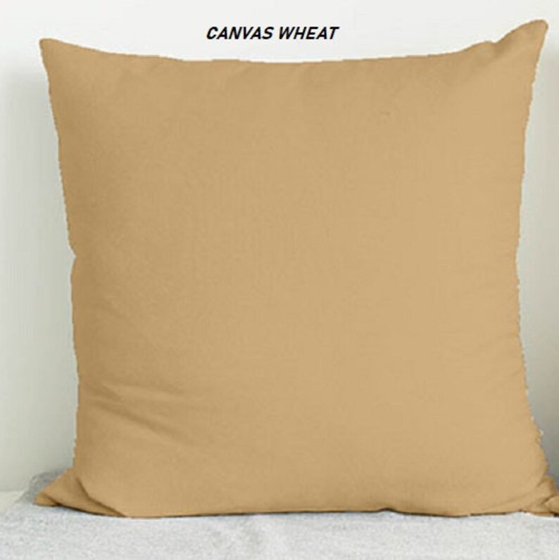 May include: A plain, light brown throw pillow with the text "CANVAS WHEAT" printed on the top.