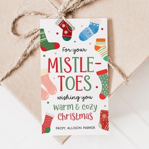 May include: A gift tag with the text "For your Mistletoes, wishing you warm & cozy Christmas" and various illustrated Christmas socks. The tag is tied to a wrapped gift with twine.