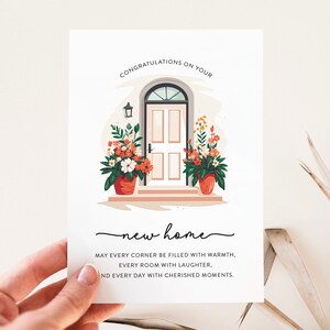 Puede incluir: Una tarjeta de felicitaci&oacute;n con una ilustraci&oacute;n dibujada a mano de una casa con una puerta de entrada y plantas en macetas. El texto dice "Felicidades por tu nueva casa. Que cada rinc&oacute;n se llene de calidez, cada habitaci&oacute;n de risas y cada d&iacute;a de momentos preciados."