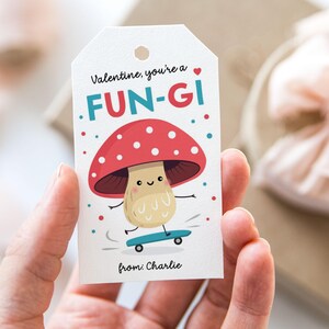 May include: A white Valentine's Day gift tag with a red and white mushroom character on a skateboard. The tag says "Valentine, you're a FUN-GI" and "from: Charlie".