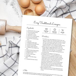 May include: A printed recipe for Easy Traditional Lasagna on a white sheet of paper. The recipe is on a wooden cutting board with eggs, a rolling pin, and a checkered cloth.