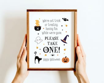 May include: A framed Halloween sign with a wooden border. The sign features a cauldron, ghost, witch hat, black cat, spiderweb, and pumpkin illustrations. Text reads "We're out trick or treating, having fun. While we're gone. PLEASE TAKE ONE! Happy Halloween."