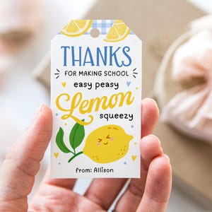 Może przedstawiać: Biała etykieta na prezent z niebieskim wzorem w kratkę na górze i ilustracją cytryny. Etykieta głosi "THANKS for making school easy peasy lemon squeezy" w kolorze niebieskim i żółtym. Etykieta jest spersonalizowana "from: Allison".