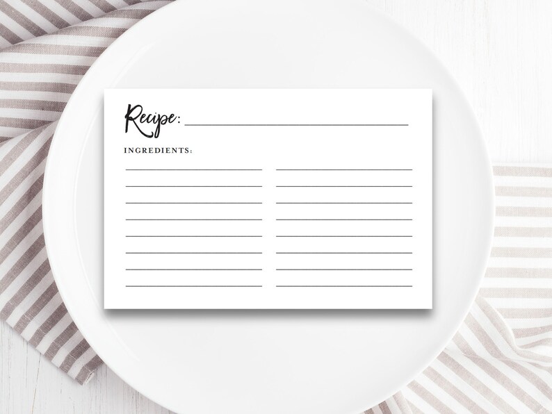 May include: A blank white recipe card with the word "Recipe" written in cursive at the top and the word "Ingredients" written below it. The card has lines for writing down the recipe and ingredients.