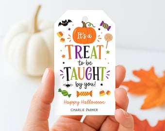 Op de afbeelding: Een wit rechthoekig cadeaulabel met een gat aan de bovenkant, voorzien van een centrale oranje pompoen en kleurrijke Halloween-afbeeldingen zoals een vleermuis, spin en snoepjes. De tekst luidt: It's a TREAT to be TAUGHT by you! Happy Halloween CHARLIE PARKER.