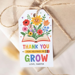 May include: A gift tag with a floral design and the words "THANK YOU FOR HELPING ME GROW" in colorful letters. The tag is tied to a wrapped gift with twine.