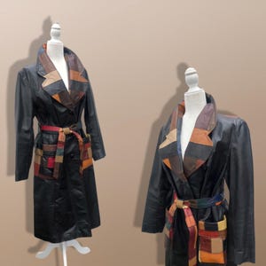 Pode incluir: Dois casacos de couro preto exibidos em manequins brancos. Cada casaco apresenta uma lapela larga e um cinto na cintura feito de um patchwork de quadrados de couro multicoloridos em tons de castanho, vermelho, azul e amarelo, com bolsos.