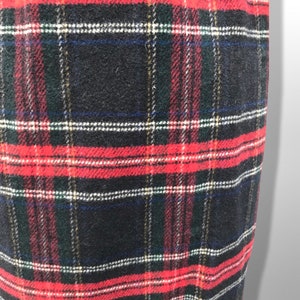 May include: Close-up of a fabric with a classic plaid pattern. The design features a grid of intersecting lines in red, black, white, green, and blue. The fabric has a textured appearance.