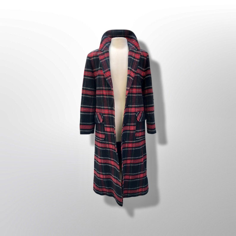 May include: A long, open coat with a classic plaid pattern in black, red, and gray. The coat features a notched collar, two front pockets, and a knee-length hem. The coat is displayed on a mannequin.