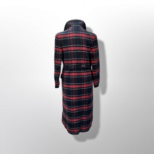 May include: A long, black and red plaid coat with a wide collar and a belted waist. The coat has long sleeves and a button closure. The plaid pattern is a classic design, suitable for fall and winter wear.
