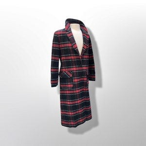 May include: A long, double-breasted coat with a classic plaid pattern in black, red, and white. The coat features a notched collar, two front pockets, and a button closure. The coat is displayed on a mannequin.