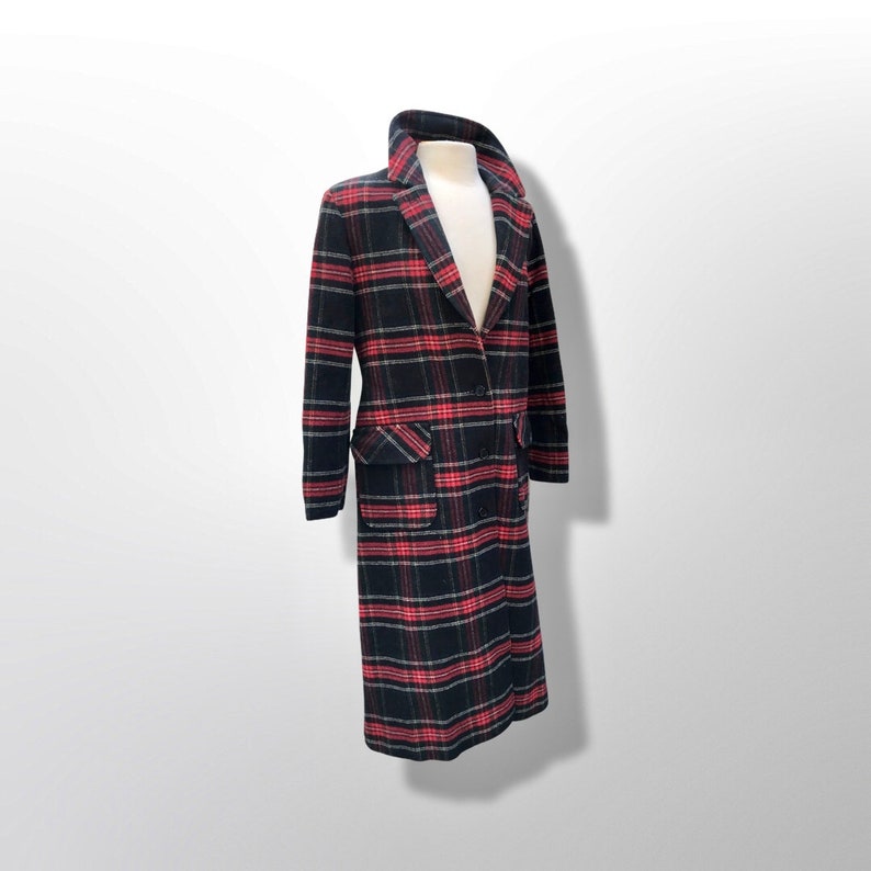 May include: A long, double-breasted coat with a classic plaid pattern in black, red, and white. The coat features a notched collar, two front pockets, and a button closure. The coat is displayed on a mannequin.