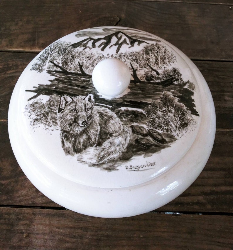 Vintage Mid Century Alaskan Art by Bering Sea Originals featuring a Wolf in a woodland scene on a round ceramic covered trinket box