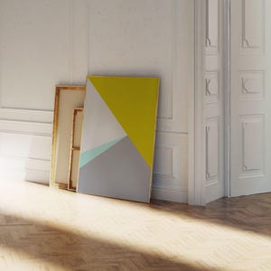 May include: A modern abstract art print leaning against a white wall. The artwork features geometric shapes in yellow, gray, and a touch of teal. The frame is a simple, clean design, suitable for contemporary decor.