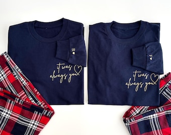 May include: Two navy blue long-sleeved shirts with gold lettering that reads "it was always you" and a gold heart.  The shirts are paired with red and black plaid pajama pants.