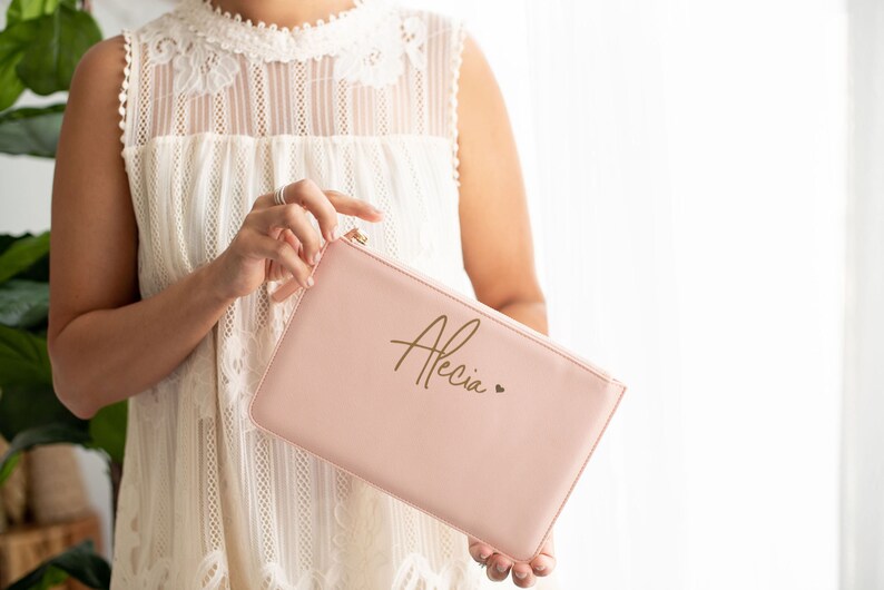 May include: A pale pink zippered pouch with the name "Alecia" written in gold script and a small gold heart.