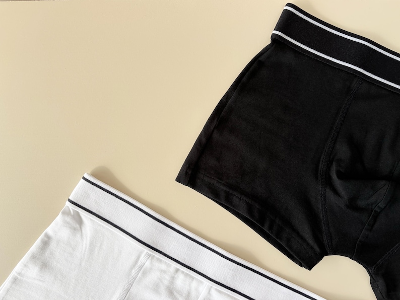 May include: Two pairs of underwear, one black and one white, with a white trim around the waistband.