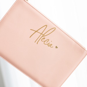 May include: A pale pink zippered pouch with the name "Alecia" written in gold script with a small gold heart.