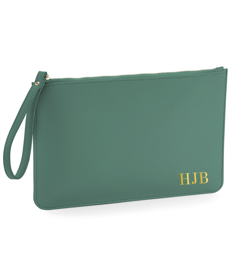 May include: A green leather clutch with a zipper closure and a wrist strap. The clutch has the initials "HJB" embossed in gold on the front.