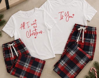 May include: Two white short-sleeved t-shirts and two pairs of red, black, and white plaid pajama pants. One shirt features the red text All I want for Christmas, and the other features ... Is You with a snowflake icon. Both pants have white drawstrings.