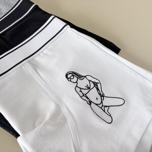 May include: White boxer shorts with a black line design and a black and white line drawing of a person in a swimsuit.