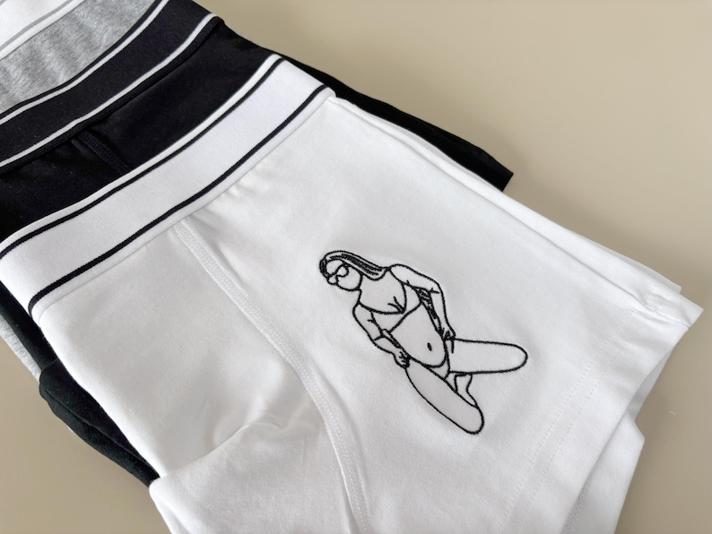 May include: White boxer shorts with a black line design and a black and white line drawing of a person in a swimsuit.
