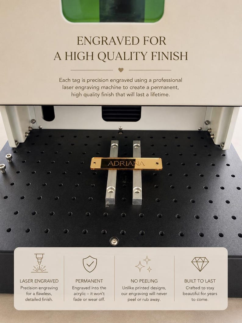 May include: A laser engraving machine with a gold-colored rectangular tag featuring the name ADRIANA centered on its black work surface. The machine displays text about high-quality finishes, precision engraving, and permanent results.