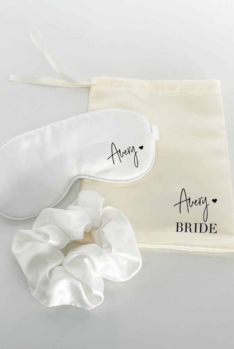 May include: White satin sleep mask, scrunchie, and a drawstring bag with the name "Avery" and the word "Bride" printed on them.