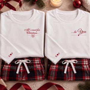 Könnte beinhalten: Zwei weiße kurzärmelige T-Shirts kombiniert mit rot-schwarz-weiß karierten Schlafanzughosen. Das linke Shirt trägt den roten Schriftzug All i want for Christmas... und das rechte ...is You. Beide Ärmel zeigen den roten Schriftzug K Herz F.