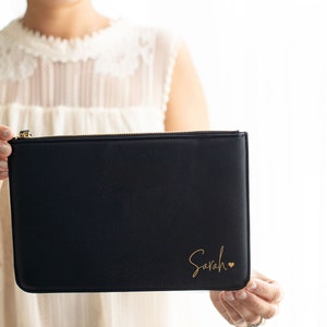 May include: A black zippered pouch with a gold zipper and the name "Sarah" written in gold script with a small gold heart.