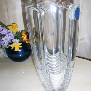 May include: A clear glass vase with a textured design. The vase has a wide mouth and a narrow base. The vase is made by the company "Cristal d'Arques".
