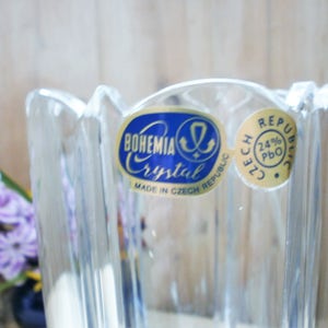 May include: A clear glass vase with a fluted design. The vase has a blue and gold label that reads "Bohemia Crystal Made in Czech Republic" and "Czech Republic 24% PbO".