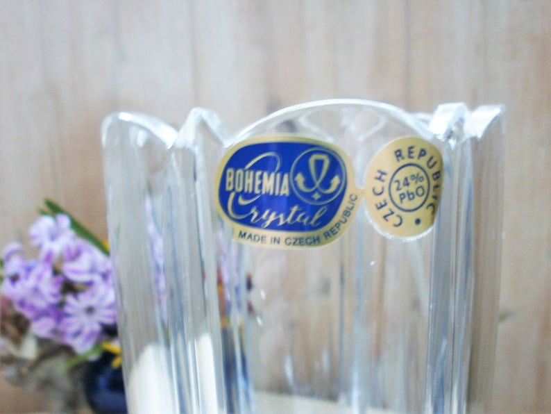 May include: A clear glass vase with a fluted design. The vase has a blue and gold label that reads "Bohemia Crystal Made in Czech Republic" and "Czech Republic 24% PbO".