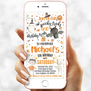 May include: A smartphone displays a Halloween-themed birthday invitation. The design features a bat, pumpkin, ghost, and the text "Join us for spooky tricks and birthday treats to celebrate Michael's 5th Birthday Saturday October 5th".