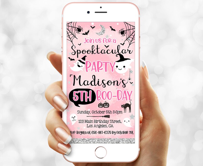 May include: A pink smartphone screen displays a Halloween party invitation. The invitation features a spooky theme with ghosts, bats, and spiderwebs. Text reads "Spooktacular Party" for Madison's 5th Boo-Day, with date, time, and location details.