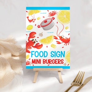 Könnte beinhalten: Rechteckiges Essensschild auf einer Holzstaffelei. Der weiße Hintergrund zeigt rote Hummer, Zitronen und einen Kochtopf. Der Text "FOOD SIGN MINI BURGERS" ist in Blau und Rot dargestellt.