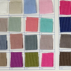 May include: A fabric swatch card displaying a range of colours and textures. The card is divided into sections, each featuring a different colour or texture. The colours include white, light blue, pink, green, blue, red, yellow, orange, brown, black, and grey. The textures include smooth, ribbed, and textured.