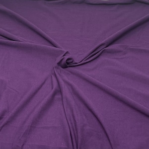 May include: A close-up of a smooth, purple fabric with a soft, wrinkled texture.