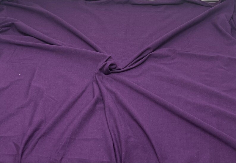 May include: A close-up of a smooth, purple fabric with a soft, wrinkled texture.